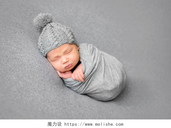在灰色的床铺上的小婴儿婴儿睡觉蜷缩在灰色毯子